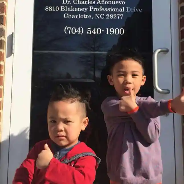Two little boys standing in front of the office front door